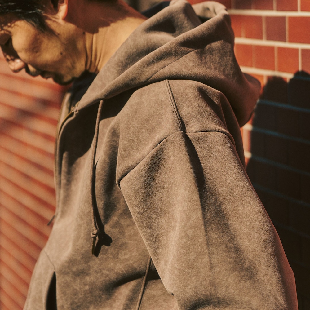 ブラウン系のライダースジャケット、ベージュ系のスラックス、ベージュ系のパーカーを着用したメンズの冬コーディネートの4枚目の写真