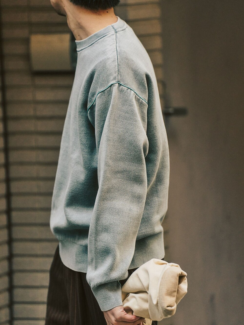 グレー系のニット/セーター、ベージュ系のその他アウター、ブラウン系のスラックスを着用したメンズの冬コーディネートの7枚目の写真