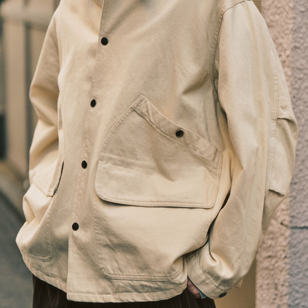 グレー系のニット/セーター、ベージュ系のその他アウター、ブラウン系のスラックスを着用したメンズの冬コーディネートの3枚目の写真