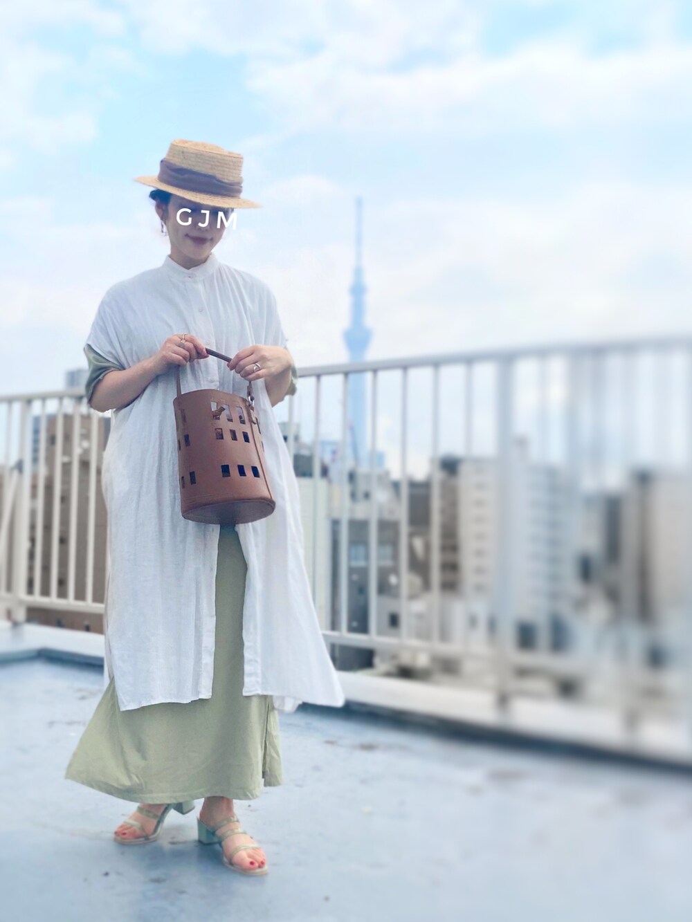 ホワイト系のシャツワンピース、ブラウン系のバッグ、グリーン系のワンピースを着用したレディースの春コーディネートの3枚目の写真