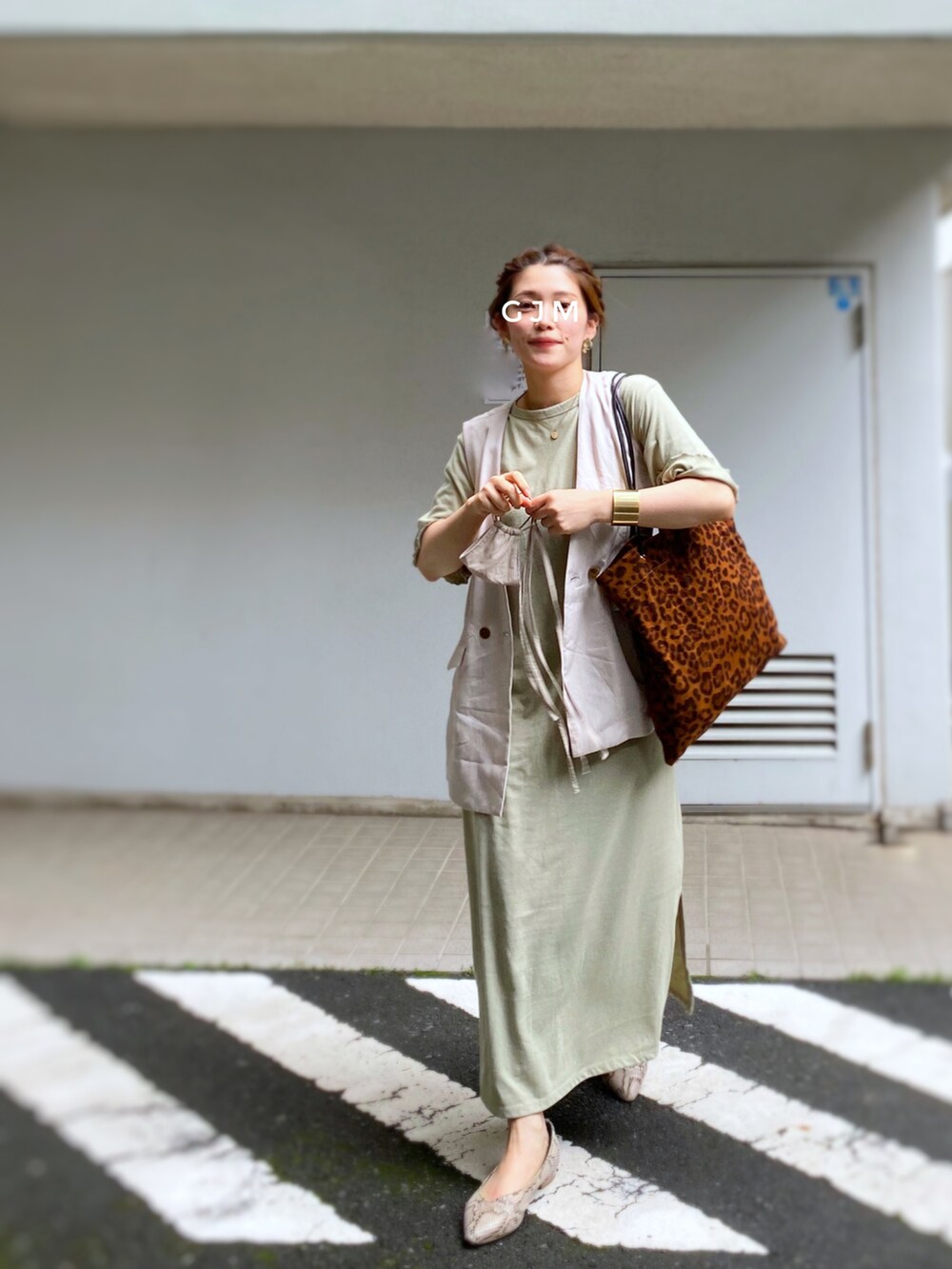 グリーン系のワンピース、ベージュ系のベスト、ブラウン系のトートバッグを着用したレディースの春コーディネートの2枚目の写真