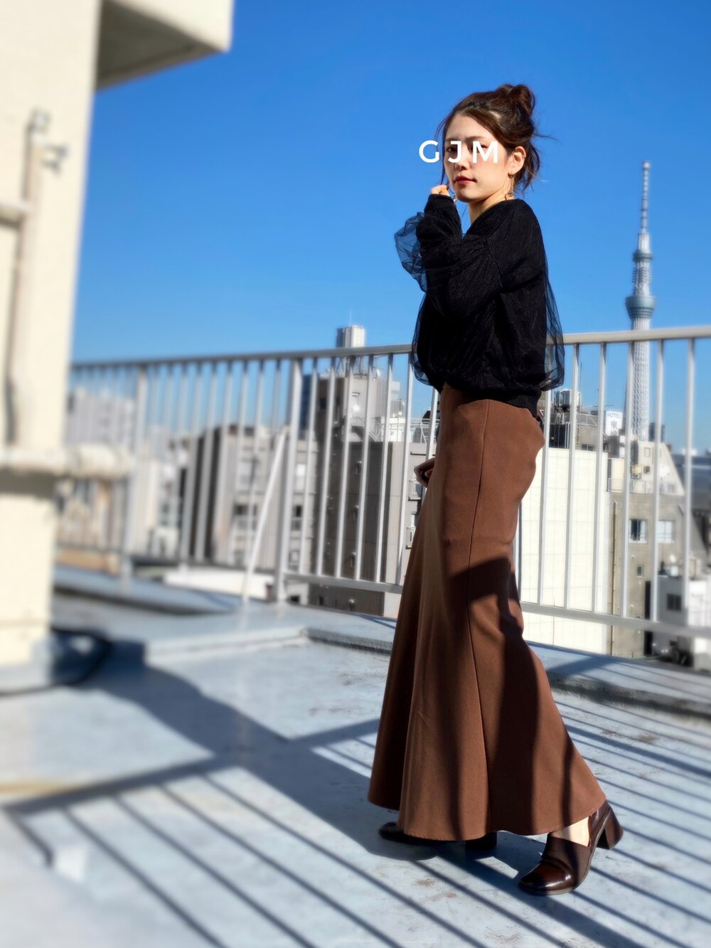 ブラック系のニット/セーター、ホワイト系のニット/セーター、ブラウン系のスカートを着用したレディースの秋コーディネートの2枚目の写真