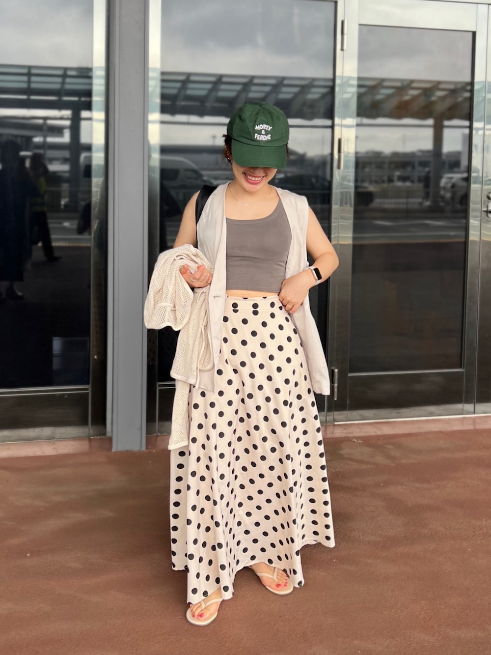 ベージュ系のスカート、グレー系のタンクトップ、ベージュ系のベストを着用したレディースの夏コーディネートの2枚目の写真