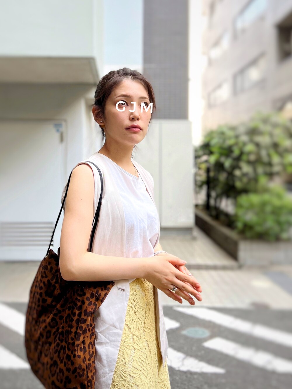 イエロー系のスカート、ブラック系のサンダル、ブラウン系のトートバッグを着用したレディースの春コーディネートの2枚目の写真