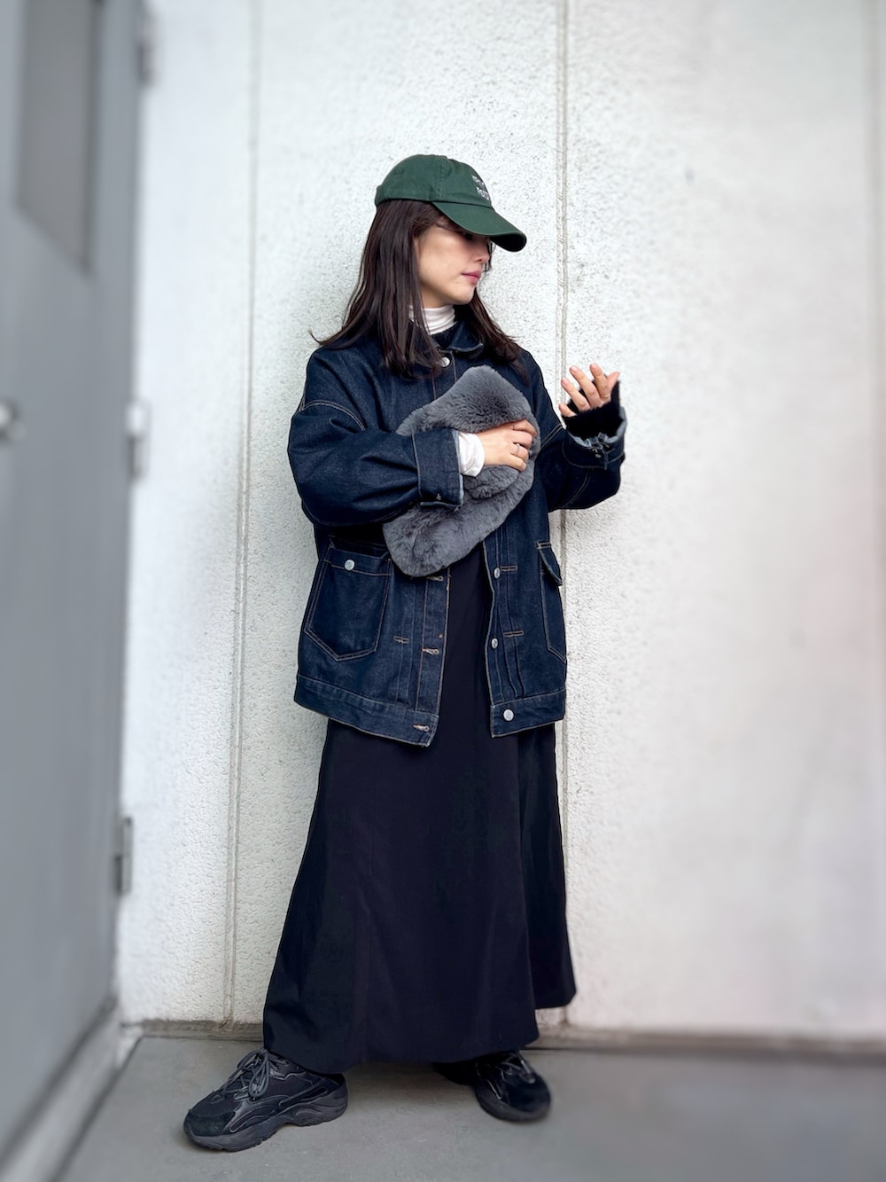 ブラック系のスニーカー、ブラック系のワンピース、ブルー系のデニムジャケットを着用したレディースの冬コーディネートの2枚目の写真