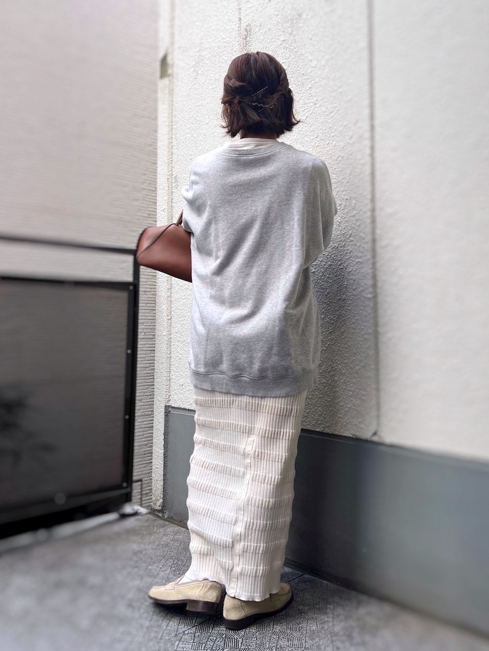 グレー系のスウェット、ホワイト系のスカート、ホワイト系のローファーを着用したレディースの秋コーディネートの2枚目の写真