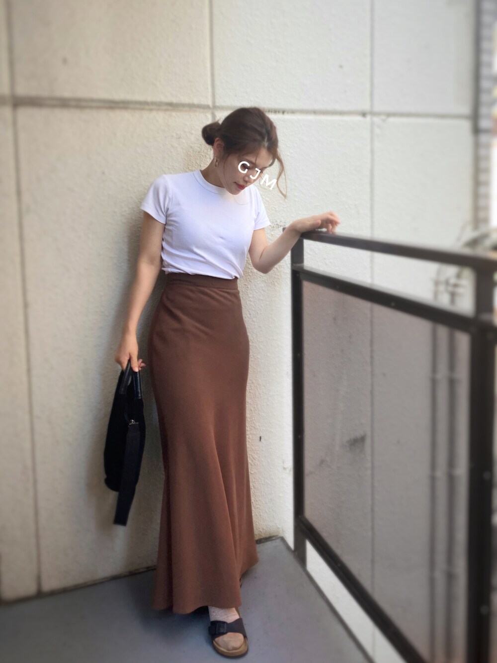 ブラック系のショルダーバッグ、ブラウン系のスカート、ホワイト系のTシャツ/カットソーを着用したレディースの夏コーディネートの2枚目の写真