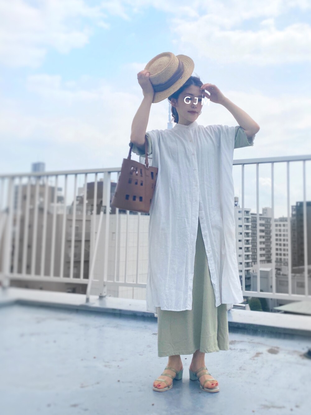 ホワイト系のシャツワンピース、ブラウン系のバッグ、グリーン系のワンピースを着用したレディースの春コーディネートの2枚目の写真