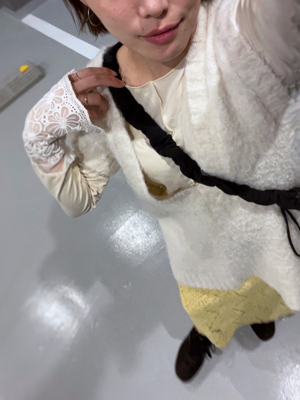 ブラック系のショルダーバッグ、ベージュ系のTシャツ/カットソー、ホワイト系のニット/セーターを着用したレディースの冬コーディネートの3枚目の写真