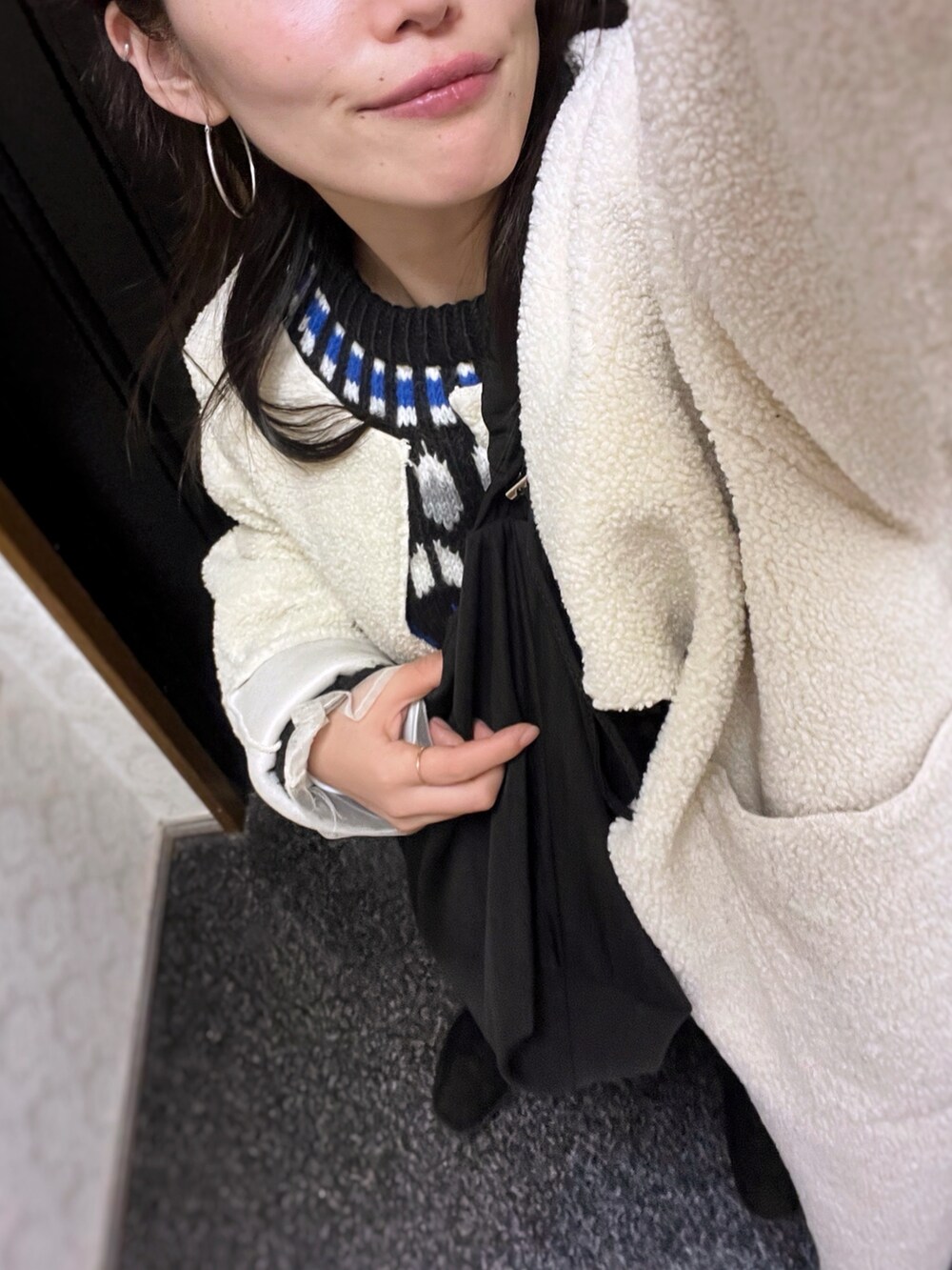 ホワイト系のムートンコート、ブラック系のニット/セーター、ブラック系のショルダーバッグを着用したレディースの冬コーディネートの2枚目の写真