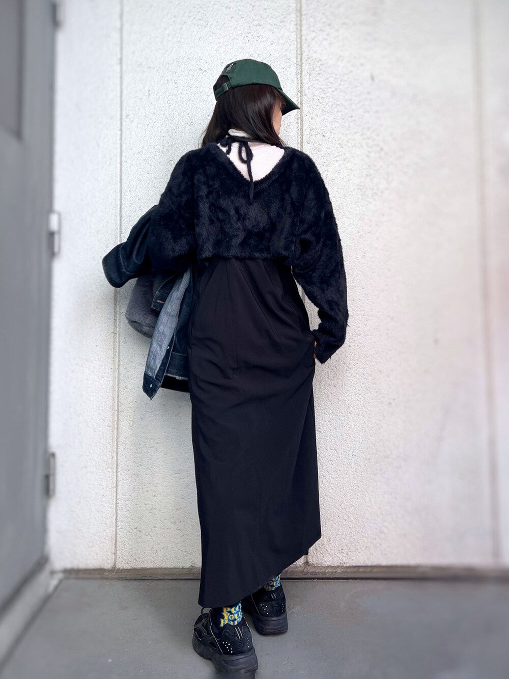 ブラック系のスニーカー、ブラック系のワンピース、ブルー系のデニムジャケットを着用したレディースの冬コーディネートの4枚目の写真