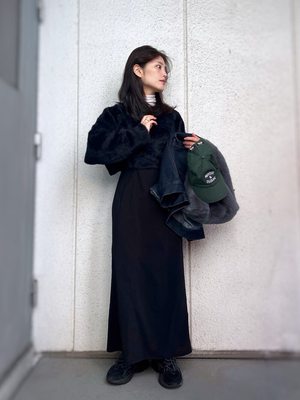 ブラック系のスニーカー、ブラック系のワンピース、ブルー系のデニムジャケットを着用したレディースの冬コーディネートの3枚目の写真