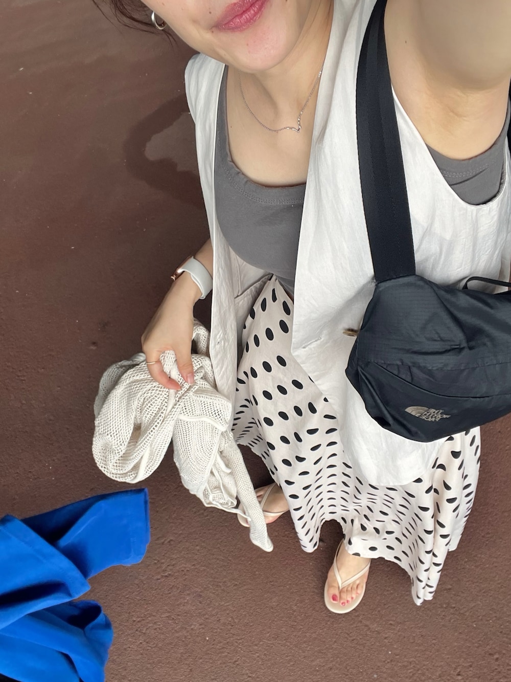 ベージュ系のスカート、グレー系のタンクトップ、ベージュ系のベストを着用したレディースの夏コーディネートの3枚目の写真