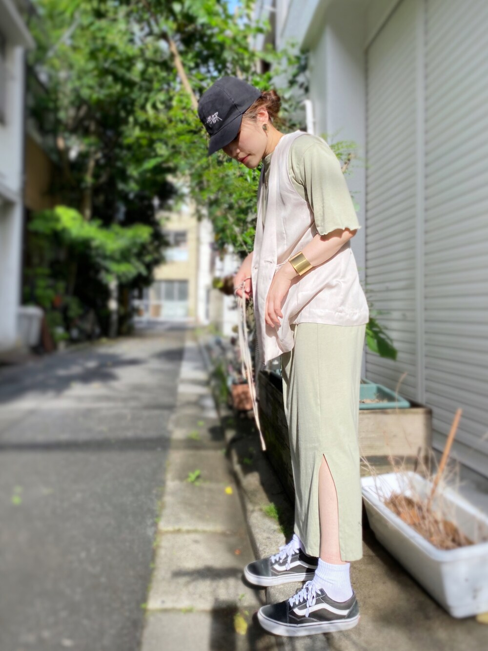 グリーン系のワンピース、ベージュ系のベスト、ブラウン系のトートバッグを着用したレディースの春コーディネートの3枚目の写真