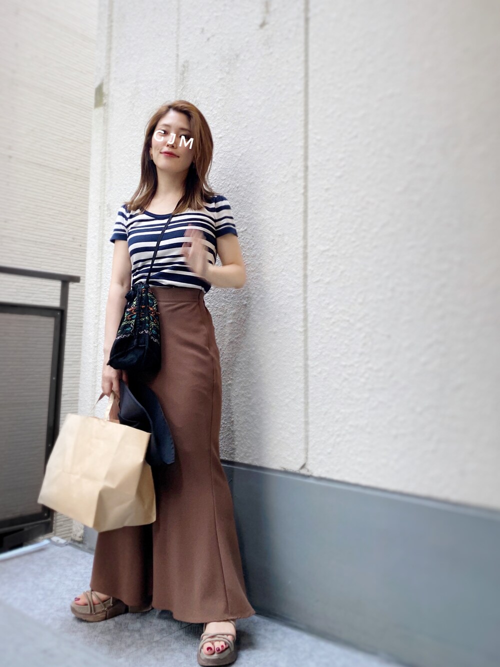 ブルー系のニット/セーター、ブラウン系のスカート、ブラック系のショルダーバッグを着用したレディースの夏コーディネートの2枚目の写真