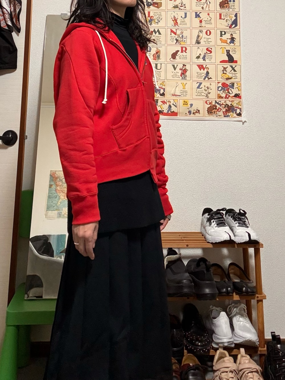 ブラック系のニット/セーター、レッド系のパーカー、ブラック系のスカートを着用したレディースの冬コーディネートの3枚目の写真
