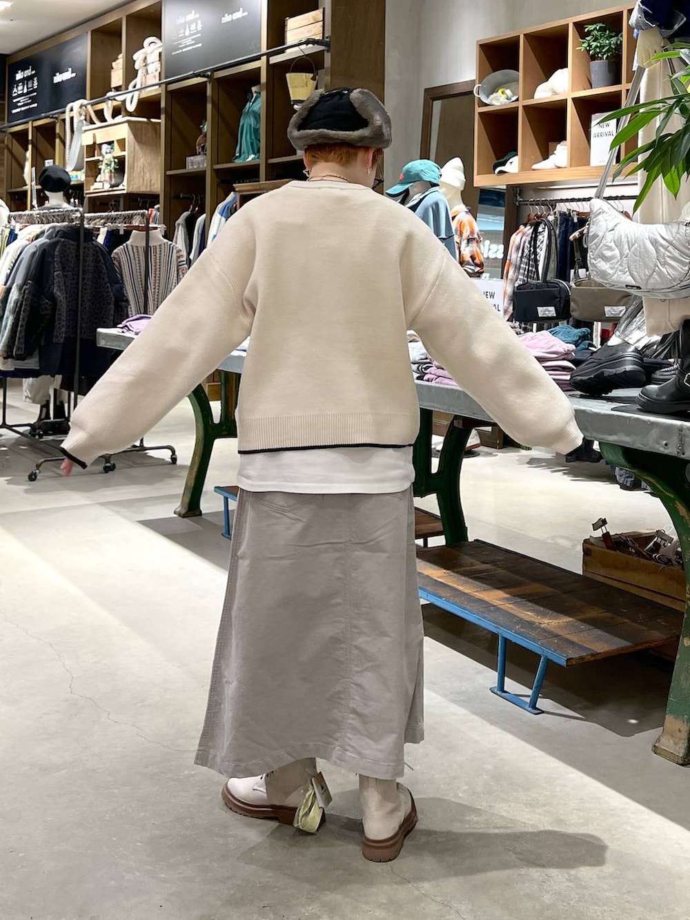 グレー系のスカート、ベージュ系のニット/セーター、ホワイト系のブーツを着用したレディースの秋コーディネートの2枚目の写真