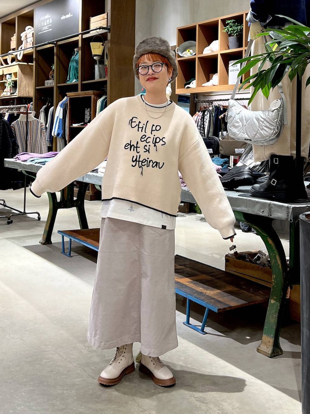 グレー系のスカート、ベージュ系のニット/セーター、ホワイト系のブーツを着用したレディースの秋コーディネートの4枚目の写真