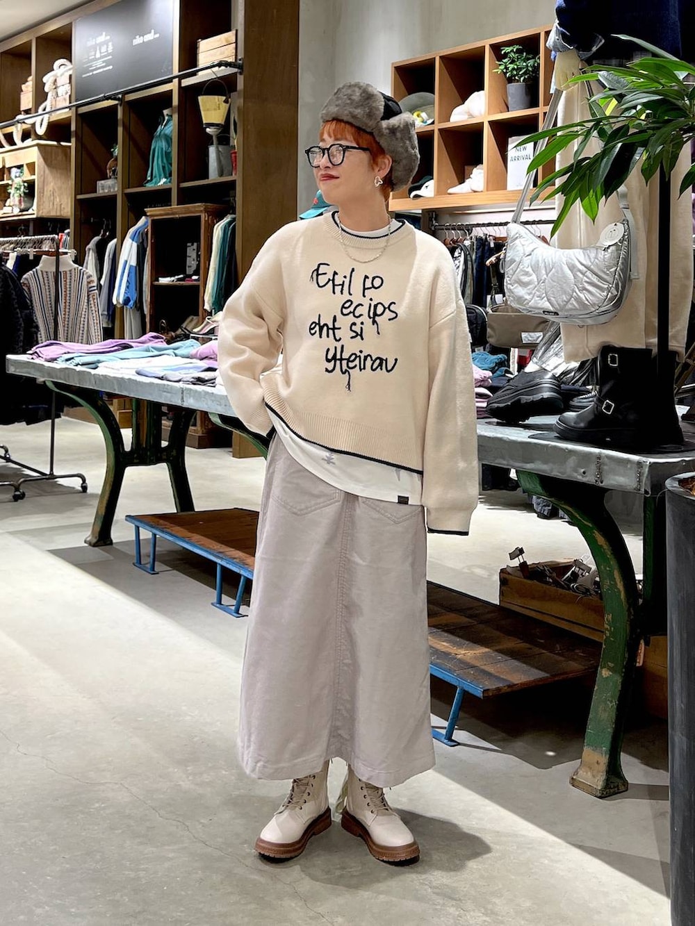 グレー系のスカート、ベージュ系のニット/セーター、ホワイト系のブーツを着用したレディースの秋コーディネートの3枚目の写真