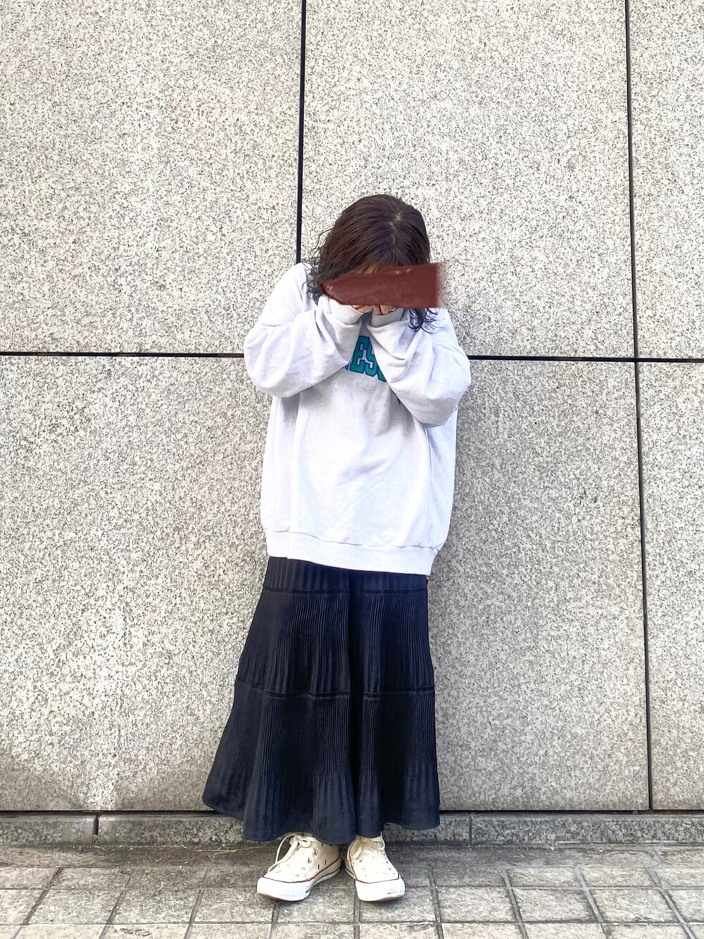 グレー系のスウェット、ブラック系のスカート、ホワイト系のスニーカーを着用したレディースの春コーディネートの4枚目の写真