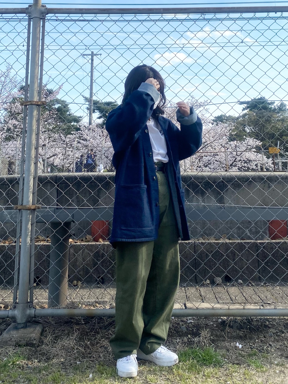 ブルー系のデニムジャケット、グリーン系のカーゴパンツ、ホワイト系のスニーカーを着用したレディースの春コーディネートの3枚目の写真