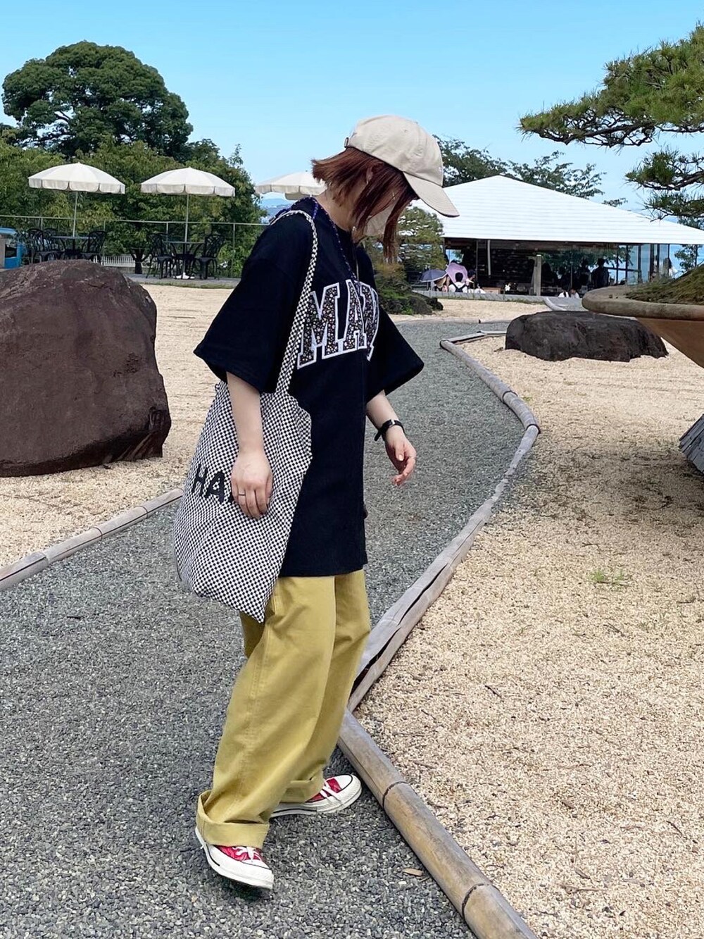 ブラック系のTシャツ/カットソー、イエロー系のその他パンツ、ベージュ系のキャップを着用したレディースの秋コーディネートの2枚目の写真