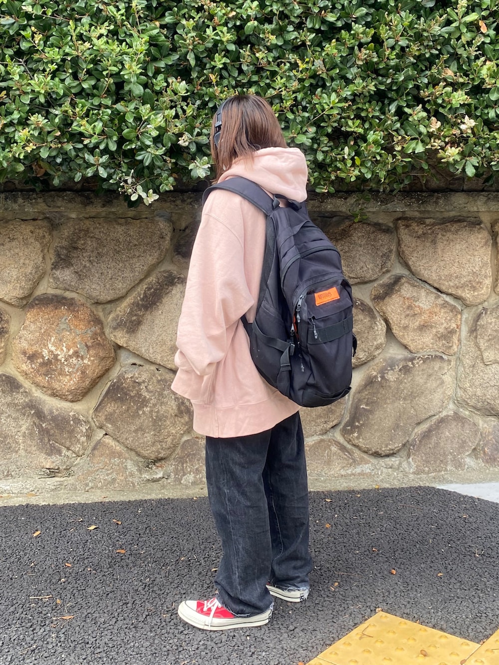 ブラック系のデニムパンツ、ブラック系のバックパック/リュック、ピンク系のパーカーを着用したレディースの秋コーディネートの3枚目の写真
