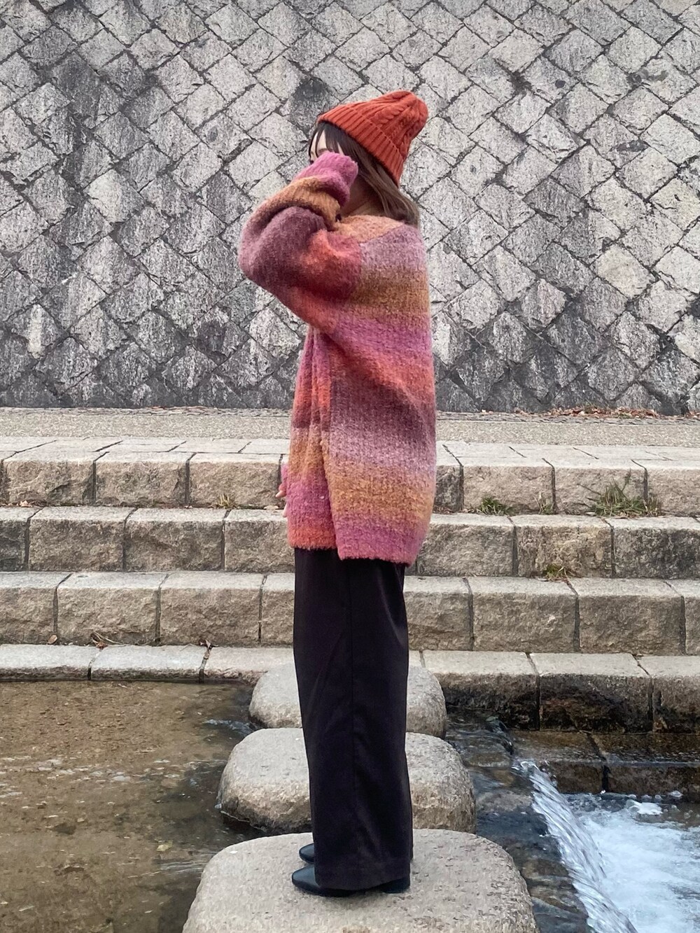 ピンク系のニット/セーター、ブラウン系のその他パンツ、ブラック系のブーツを着用したレディースの冬コーディネートの2枚目の写真