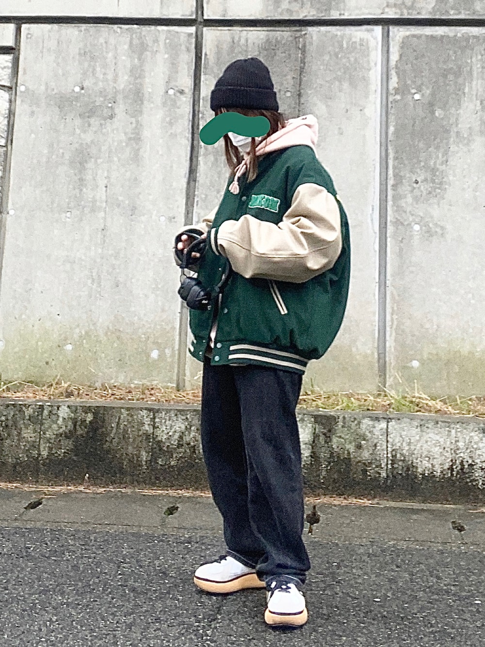 グリーン系のスタジャン、ブラック系のデニムパンツ、ホワイト系のスニーカーを着用したレディースの秋コーディネートの2枚目の写真