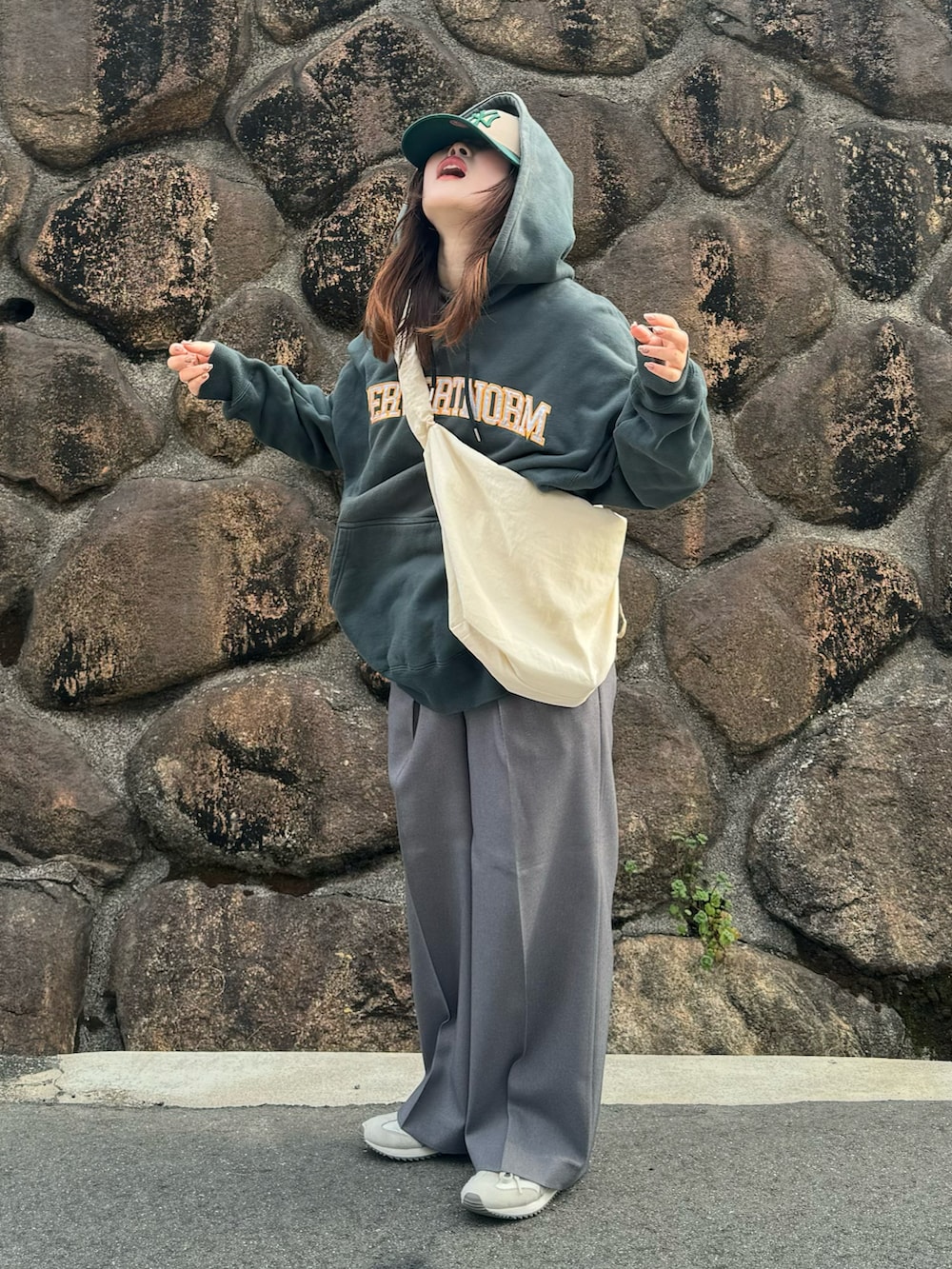 ベージュ系のスニーカー、グレー系のスラックス、ホワイト系のショルダーバッグを着用したレディースの春コーディネートの2枚目の写真