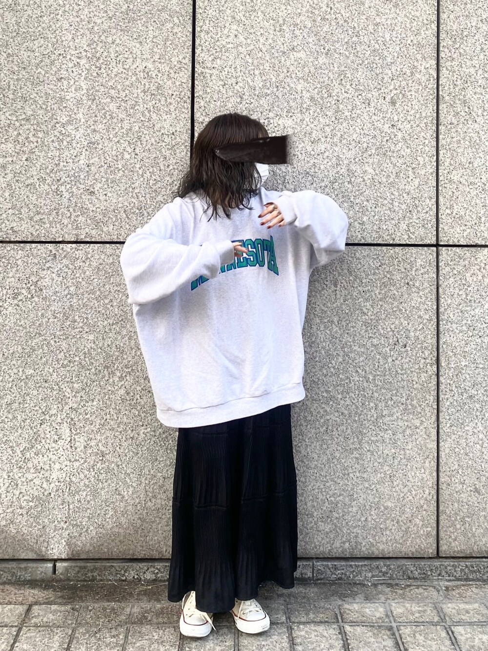 グレー系のスウェット、ブラック系のスカート、ホワイト系のスニーカーを着用したレディースの春コーディネートの2枚目の写真