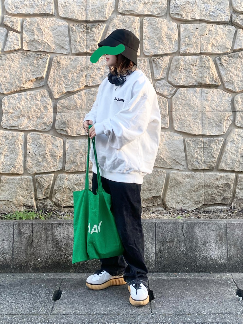 ブラック系のデニムパンツ、ホワイト系のスニーカー、グリーン系のトートバッグを着用したレディースの冬コーディネートの2枚目の写真