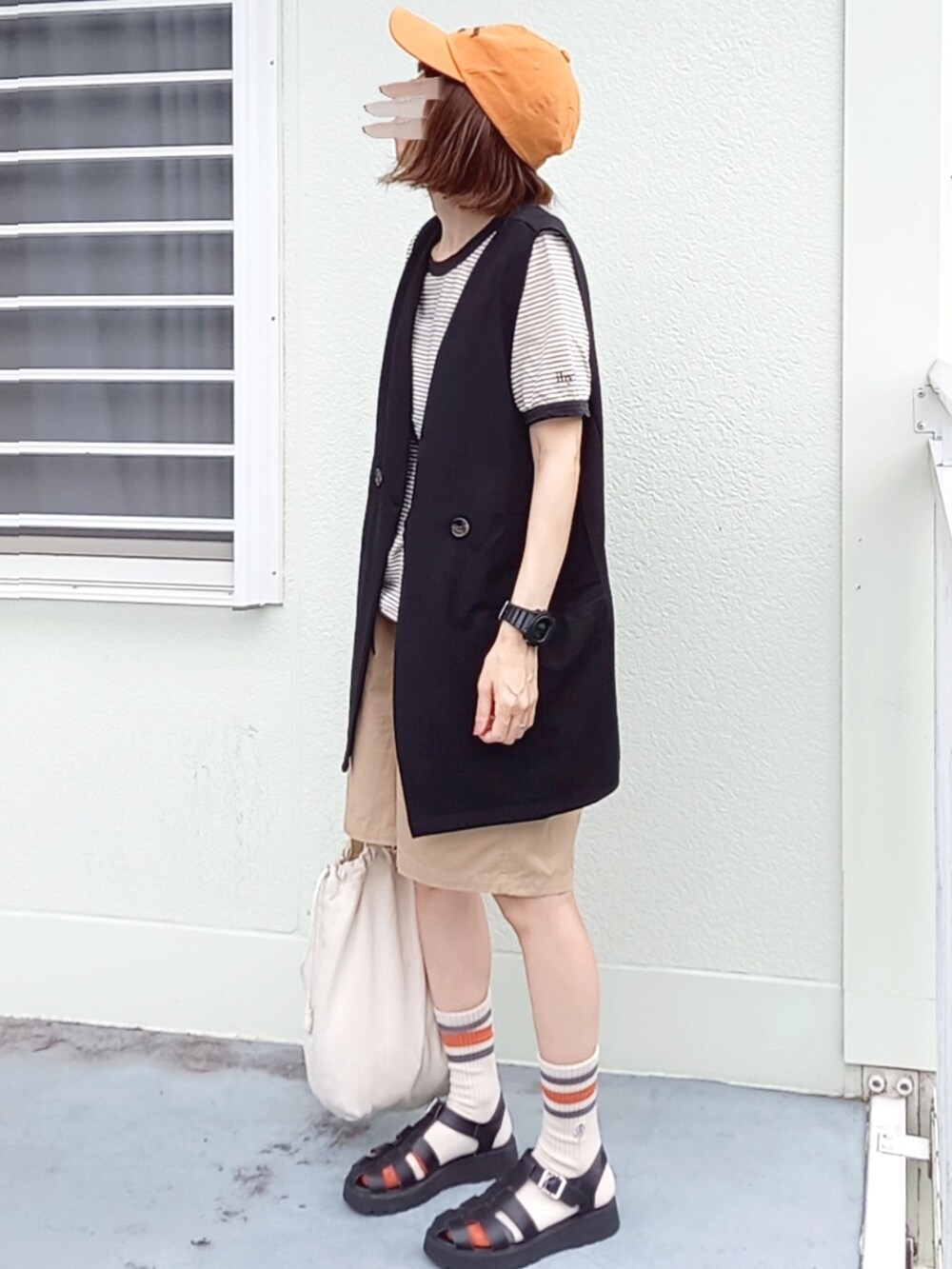 ブラック系のベスト、ブラック系のTシャツ/カットソー、ベージュ系のチノパンツを着用したレディースの夏コーディネートの2枚目の写真