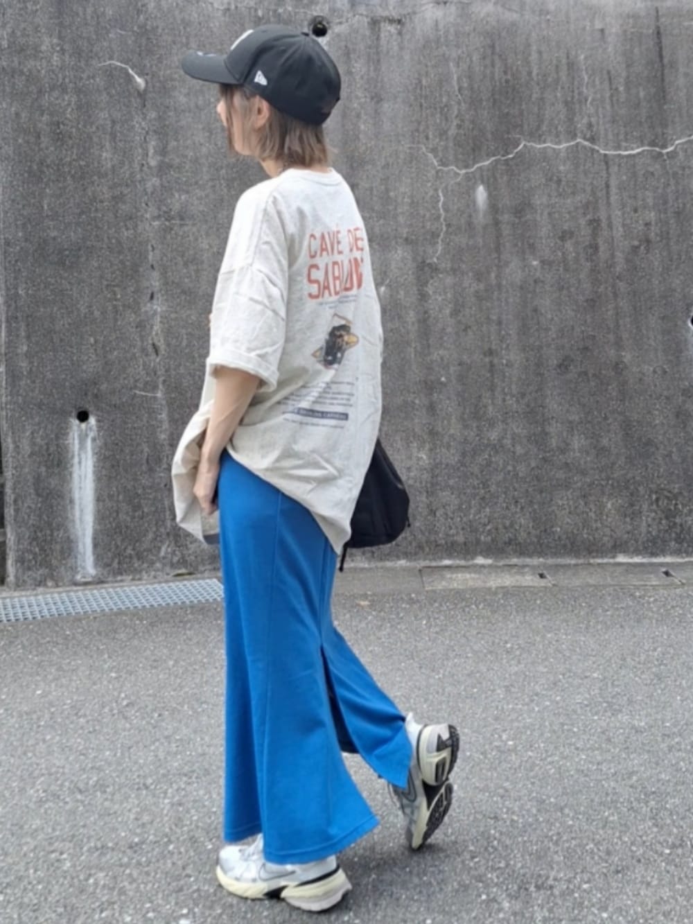 オレンジ系のTシャツ/カットソー、ブルー系のスカート、ホワイト系のスニーカーを着用したレディースの夏コーディネートの2枚目の写真