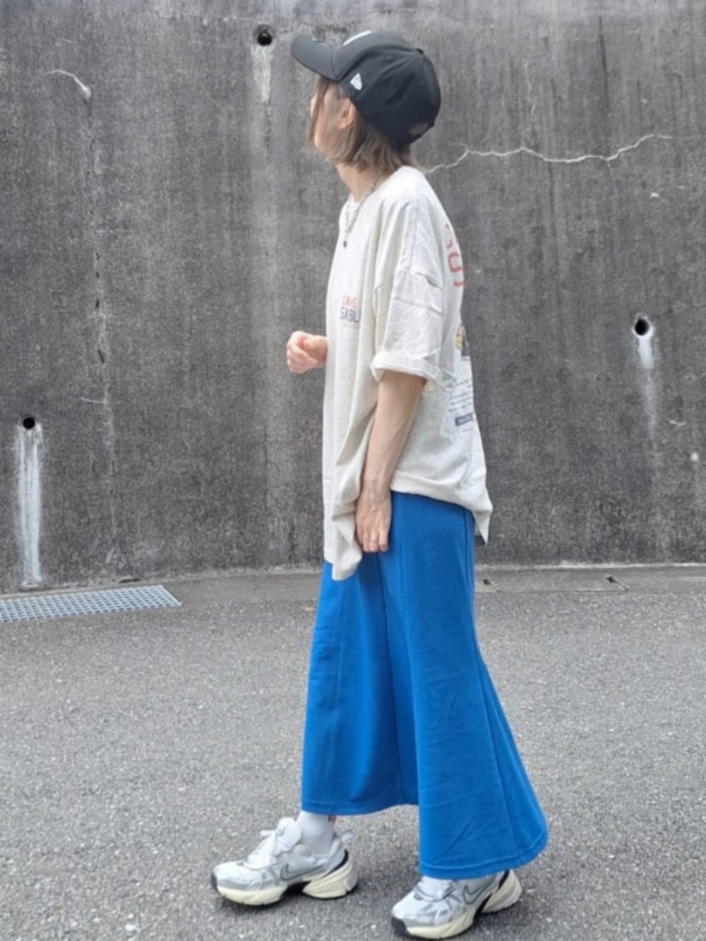 オレンジ系のTシャツ/カットソー、ブルー系のスカート、ホワイト系のスニーカーを着用したレディースの夏コーディネートの3枚目の写真