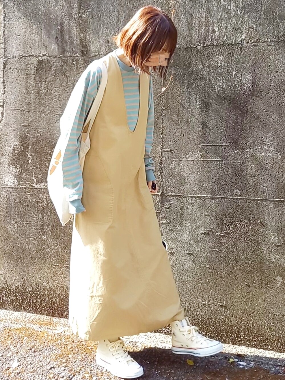 イエロー系のワンピース、グリーン系のTシャツ/カットソー、ベージュ系のトートバッグを着用したレディースの春コーディネートの3枚目の写真