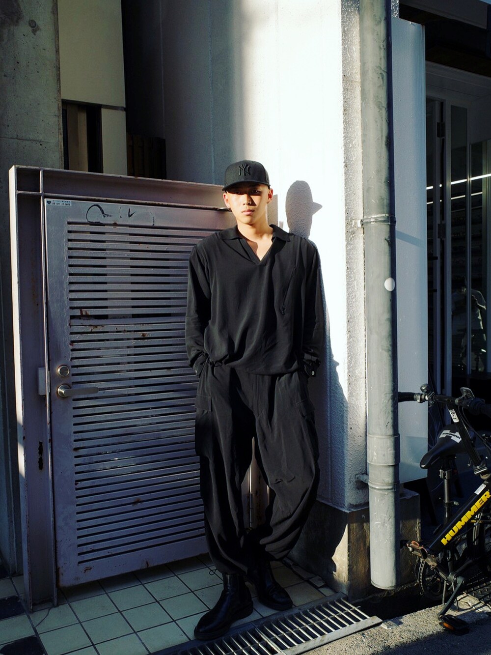 ブラック系のセットアップ、ブラック系のブーツ、ブラック系のキャップを着用したメンズの秋コーディネートの2枚目の写真