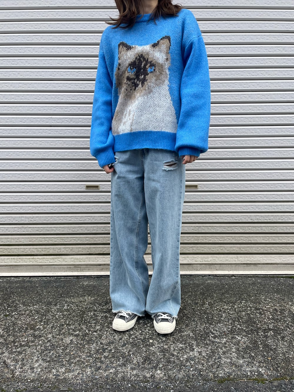 ブルー系のデニムパンツ、ブルー系のニット/セーター、ブラック系のスニーカーを着用したレディースの秋コーディネートの2枚目の写真