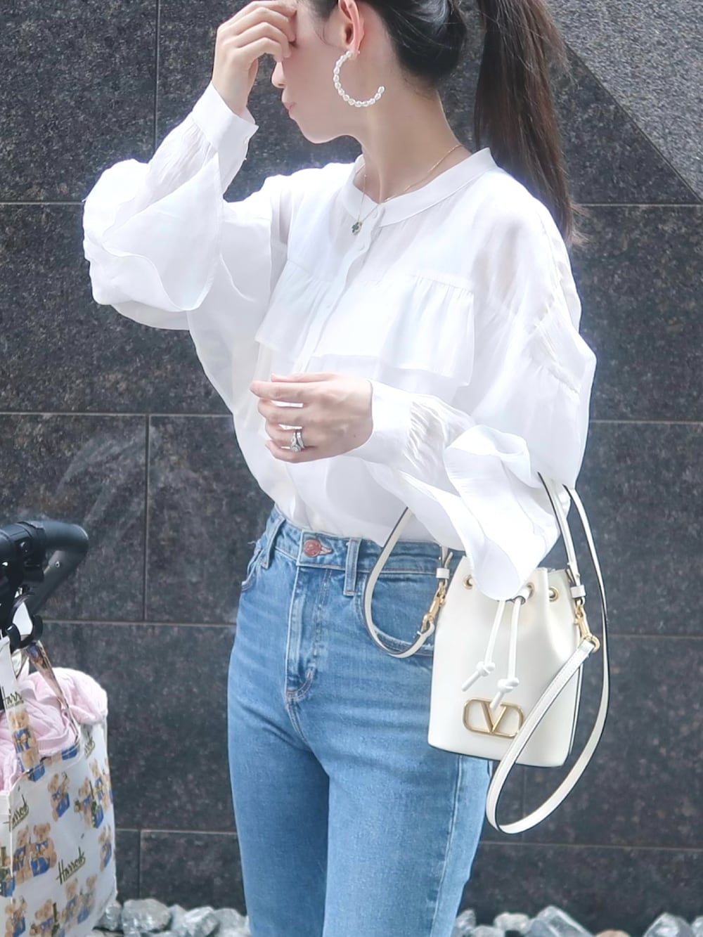 ホワイト系のトップス、ホワイト系のバッグ、ブルー系のデニムパンツを着用したレディースの春コーディネートの2枚目の写真