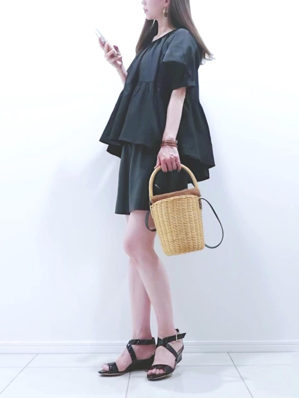 ブラウン系のかごバッグ、ブラック系のサンダル、ブラック系のシャツ/ブラウスを着用したレディースの夏コーディネートの2枚目の写真