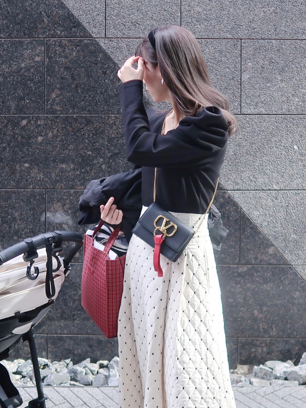 レッド系のバッグ、ブラック系のショルダーバッグ、ブラック系のトップスを着用したレディースの冬コーディネートの2枚目の写真