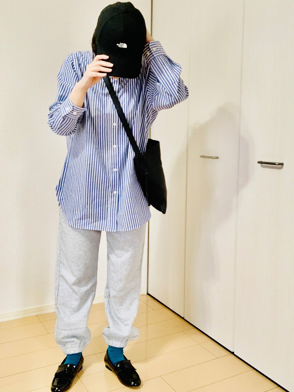 ブルー系のシャツ/ブラウス、ブラック系のショルダーバッグ、ブラック系のローファーを着用したレディースの春コーディネートの2枚目の写真