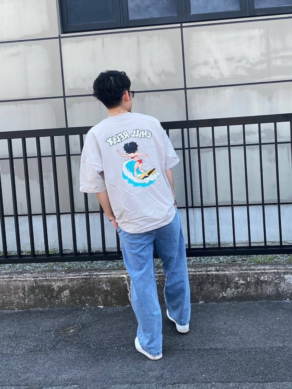 ブルー系のデニムパンツ、ホワイト系のスニーカー、グレー系のTシャツ/カットソーを着用したメンズの春コーディネートの2枚目の写真