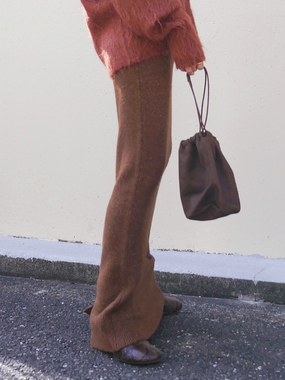 オレンジ系のカーディガン/ボレロ、ブラウン系のスカート、ブラウン系のトートバッグを着用したレディースの冬コーディネートの4枚目の写真