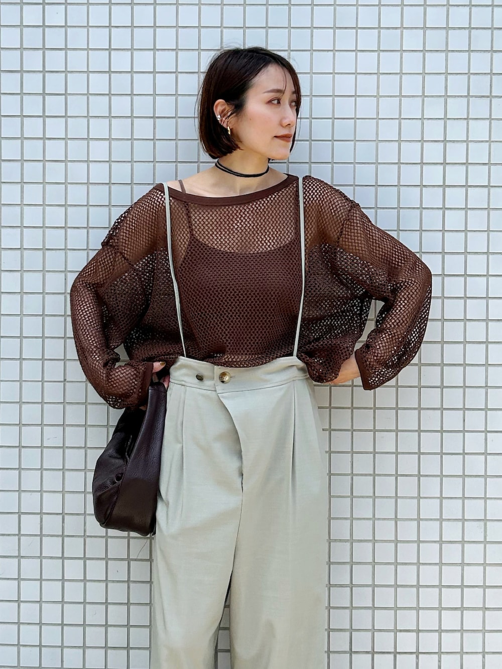 ブラウン系のTシャツ/カットソー、ベージュ系のスラックス、レッド系のハンドバッグを着用したレディースの春コーディネートの2枚目の写真