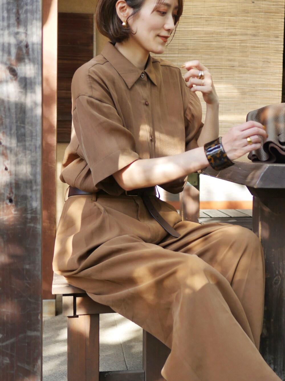 ブラウン系のシャツ/ブラウス、ブラウン系のハンドバッグ、ブラウン系のサンダルを着用したレディースの秋コーディネートの3枚目の写真