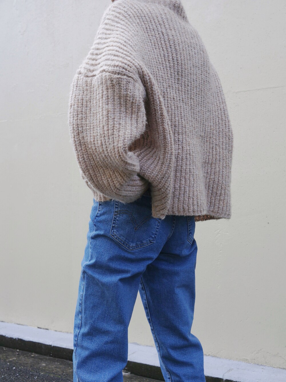 ブルー系のデニムパンツ、ブラウン系のトートバッグ、ベージュ系のニット/セーターを着用したレディースの冬コーディネートの5枚目の写真