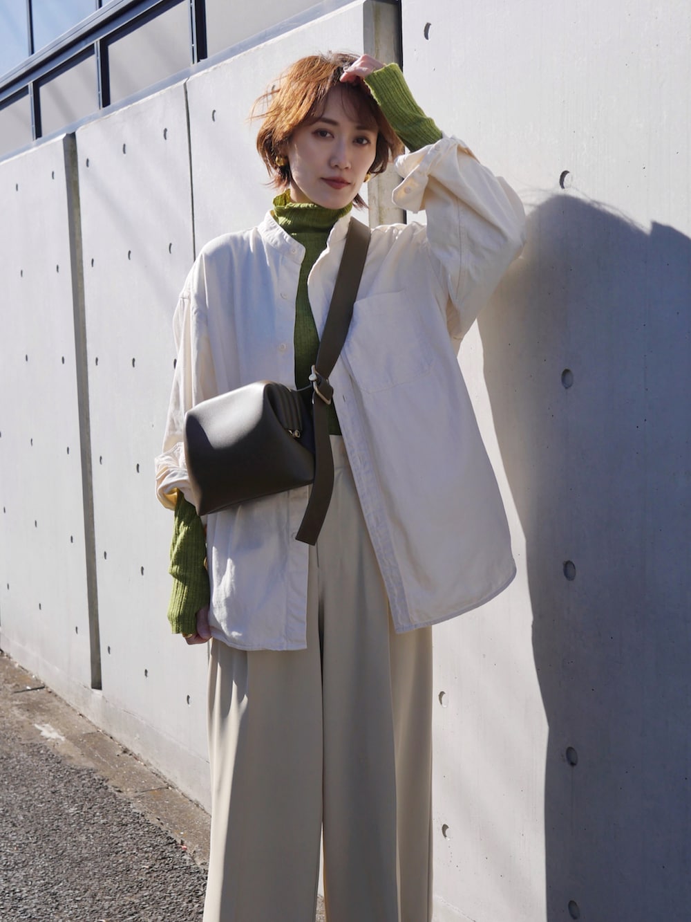 グリーン系のニット/セーター、ベージュ系のその他パンツ、ホワイト系のシャツ/ブラウスを着用したレディースの冬コーディネートの2枚目の写真