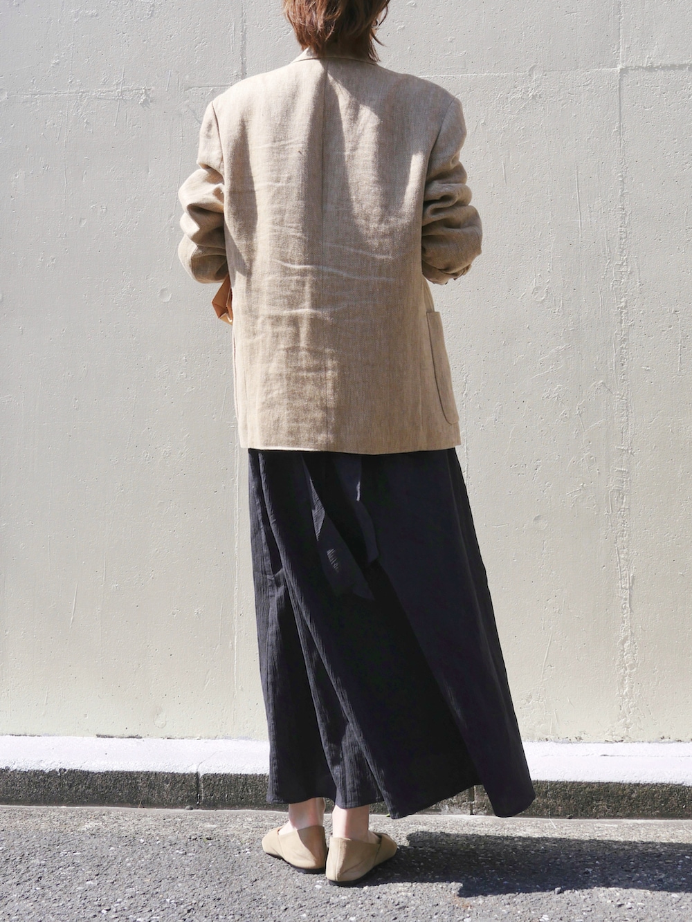 ブラック系のワンピース、ベージュ系のテーラードジャケット、ブラウン系のトートバッグを着用したレディースの春コーディネートの5枚目の写真