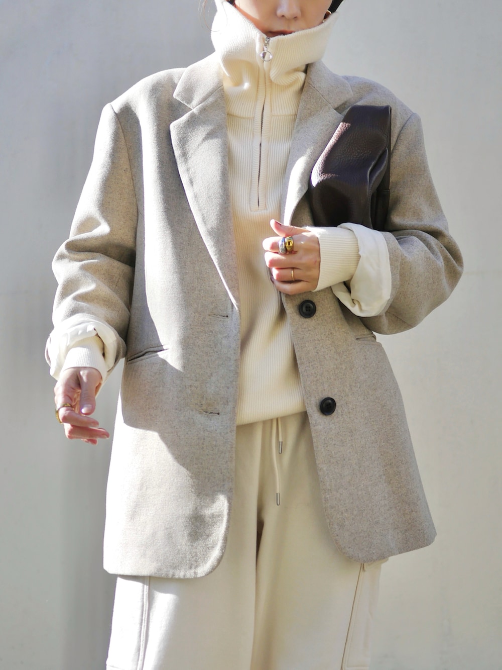 ベージュ系のテーラードジャケット、レッド系のハンドバッグ、ホワイト系のスニーカーを着用したレディースの冬コーディネートの2枚目の写真